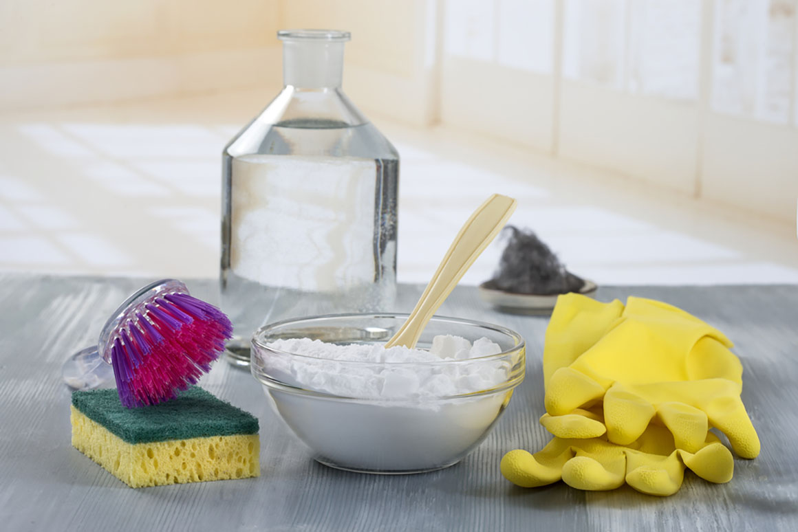 a cleaning set up with gloves brushes and baking soda and vinegar