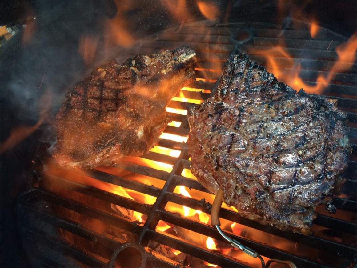 a couple of steaks being flame grilled