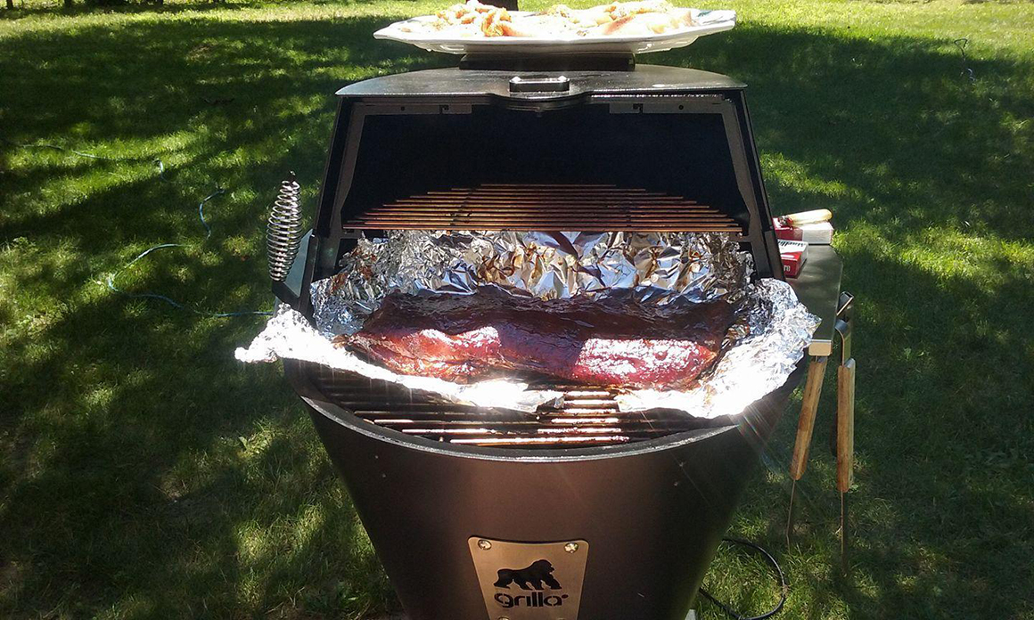 a rack of ribs wrapped in foil on a grill