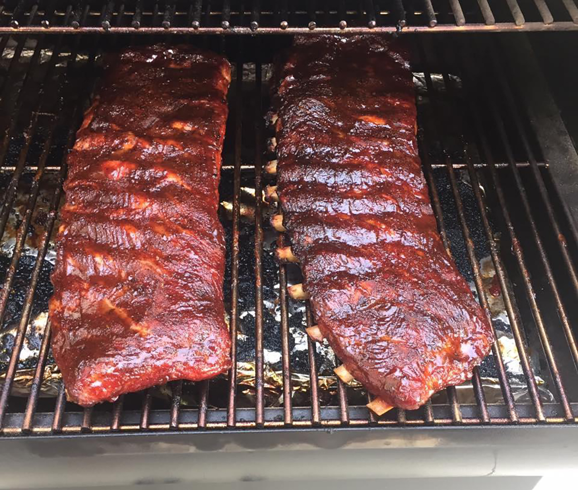 two racks of bbq ribs cooking on a grill