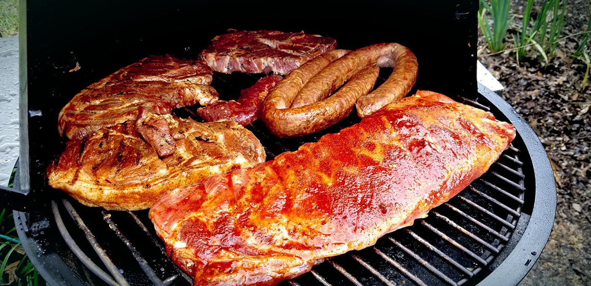 a rack of ribs on a grill with a few steaks and sausages